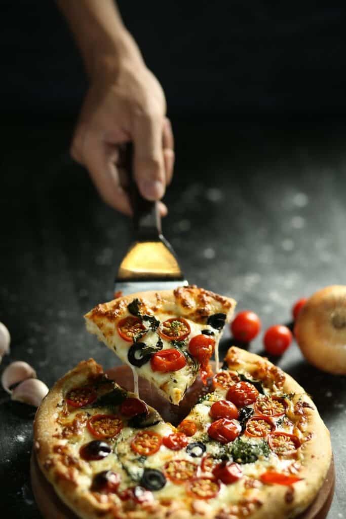 Hand serving a slice of pizza