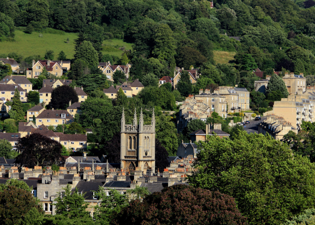 A group of houses situated on a small hilltop surrounded by trees.